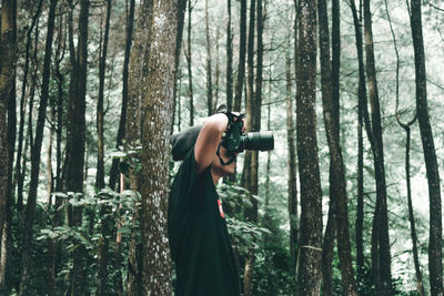 Man photographing through camera at forest