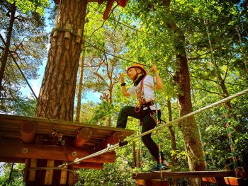 Low angle view of woman standing by tree in forest