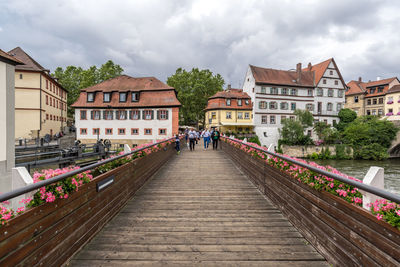 Footbridge amidst buildings in city against sky