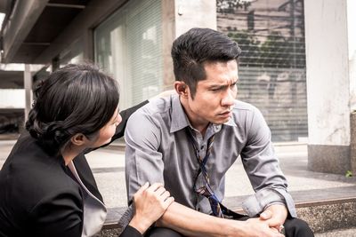 Woman consoling male friends sitting on steps