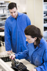 Female technician analyzing machine while colleague looking at her in industry