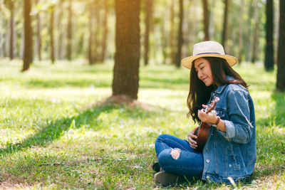 Woman playing ukulele at forest