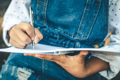 Midsection of woman writing in book