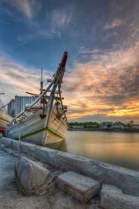 Ship moored at beach against sky during sunset