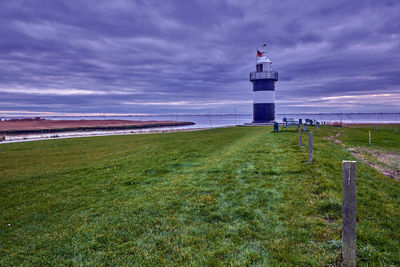 Lighthouse by sea against sky