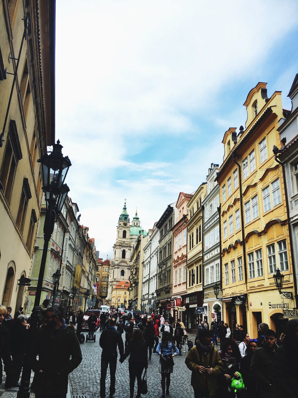 building exterior, architecture, built structure, large group of people, sky, city, street, city life, men, person, building, lifestyles, cloud - sky, walking, residential building, city street, residential structure, outdoors, cloud