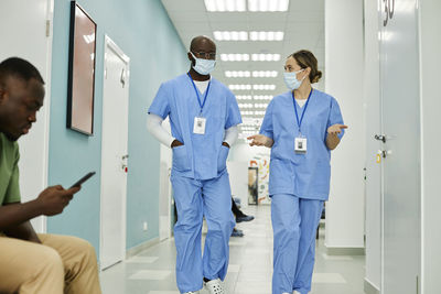 Medical colleagues discussing with each other walking in hospital corridor