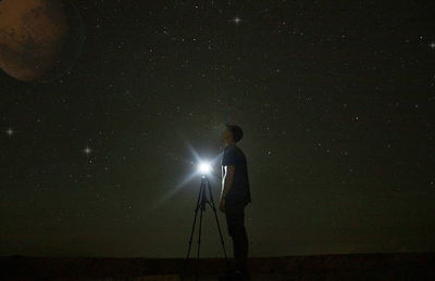 Man holding umbrella against illuminated star field at night