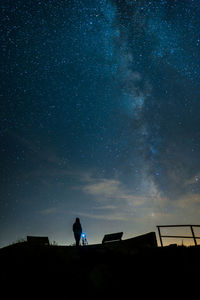 Low angle view of silhouette person standing against star field