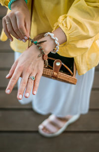 Midsection of woman holding yellow while sitting on wood