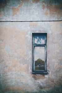 Old window in horizontal colored composition with a old dirty wall.
