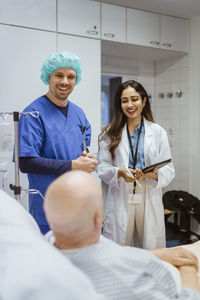 Happy healthcare workers talking to senior male patient in hospital