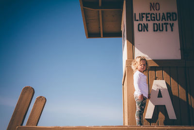 Low angle view of woman standing against blue sky