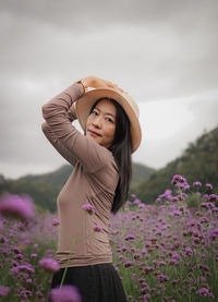 Portrait of young woman standing against sky