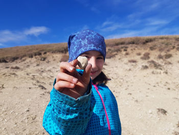 Portrait of child girl holding in her hand and showing a fossil shell