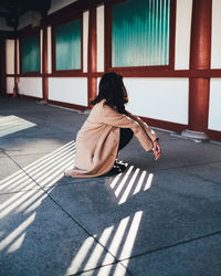 Side view of woman crouching in corridor