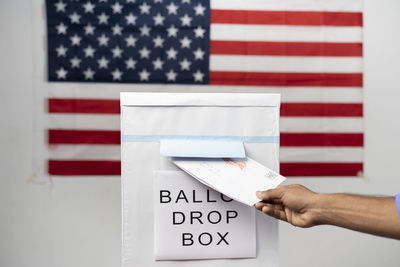 Close-up of hand holding flag against white wall