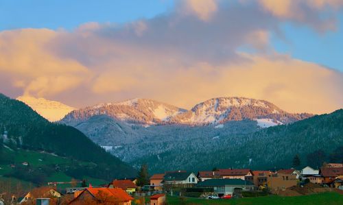 Scenic view of townscape by mountains against sky