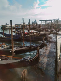 Boats moored in canal against cloudy sky