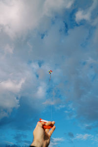 Low angle view of woman holding umbrella against sky