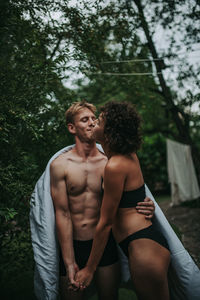 Young couple standing against trees