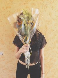 Woman holding bouquet against wall