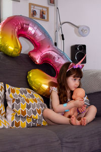 Girl sitting with balloons at home