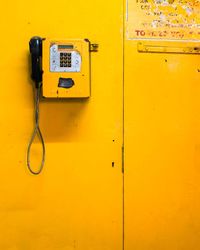 Close-up of yellow telephone on wall