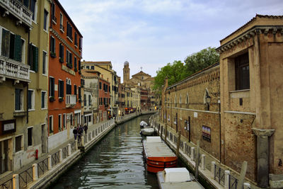 Canal amidst buildings in city against sky