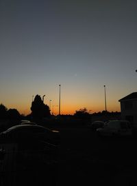 Silhouette city street against sky during sunset