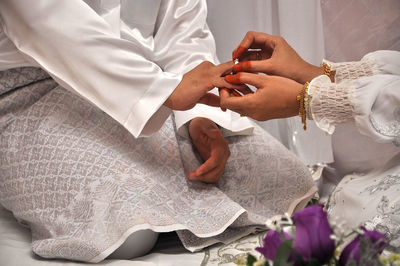 Bride putting ring on groom finger during wedding ceremony