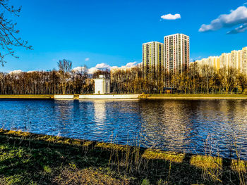Scenic view of lake by buildings against blue sky