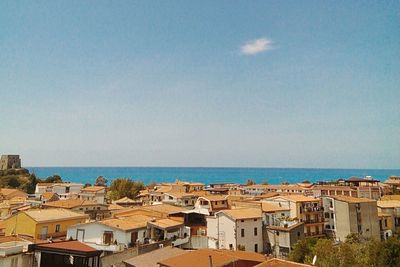 Town by sea against blue sky