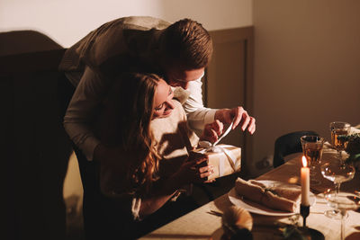 A man and a woman in love at a romantic dinner give each other gifts for christmas in the evening