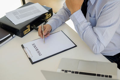 Midsection of insurance agent writing on form at office