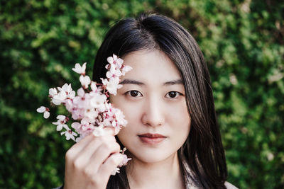 Portrait of beautiful chinese asian woman holding almond tree flowers. springtime outdoors