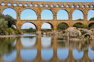 Pont du gard, the roman aqueduc in provence, reflecting in the gardon river