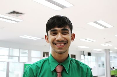 Portrait of young businessman smiling while standing in office