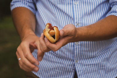 Midsection of man holding hot dog