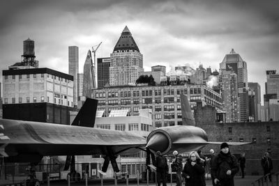 People on modern buildings in city against sky