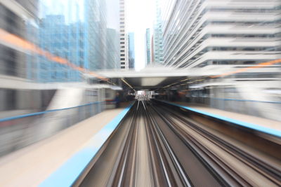 Blurred motion of railroad tracks amidst buildings in city