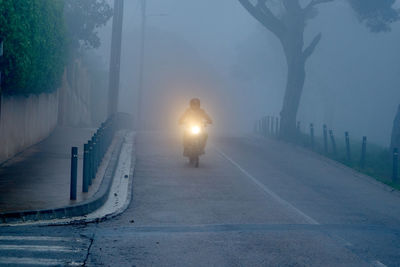 Man riding motorcycle on road in foggy weather
