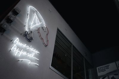 Low angle view of illuminated text on wall at night