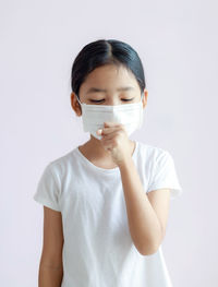 Cute girl wearing mask standing against white background