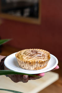 Hand with cinnamon roll with top angle