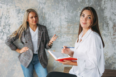 Portrait of woman holding book by colleague