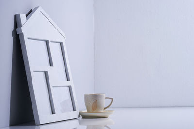 Close-up of coffee cup on table against white wall