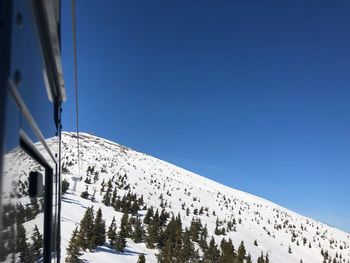 Low angle view of snowcapped mountains against clear blue sky