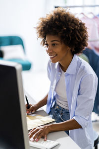 Smiling female entrepreneur using desktop computer while working at studio