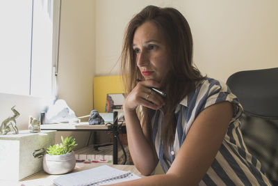 Portrait of young woman sitting on table at home